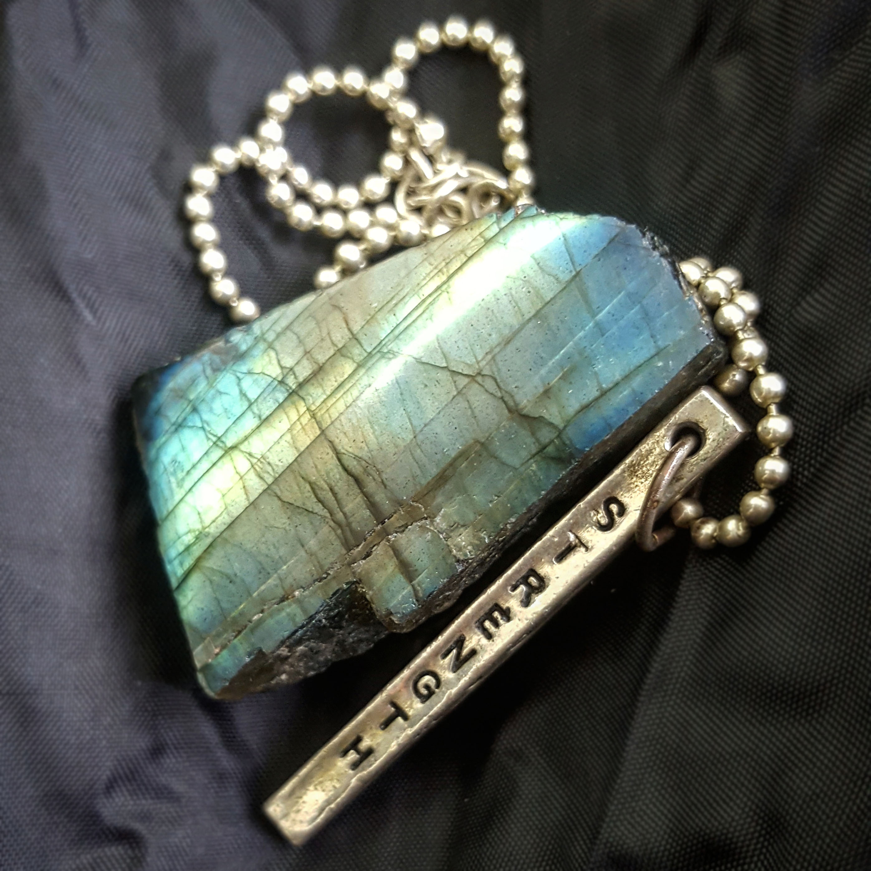 Labradorite gem stone with a necklace with Strength written on it - The Last Krystallos blog